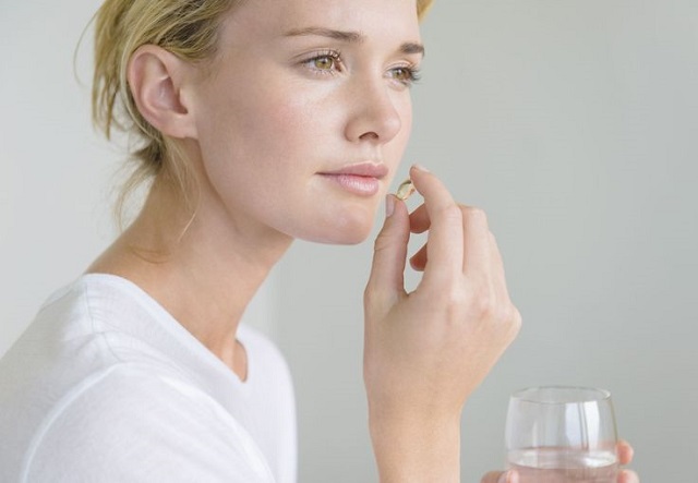 Девушка пьет таблетку
