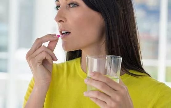 Женщина пьет таблетку